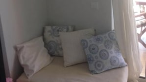 Une petite pièce agréable, avec un lit, un tableau encadré au mur et une fenêtre avec des rideaux.