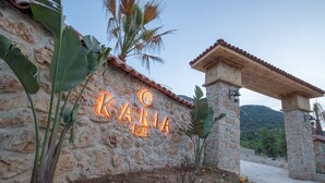 Un muro de piedra con un letrero de neón que dice "KARIA HOTEL" y una estructura de pérgola de madera.