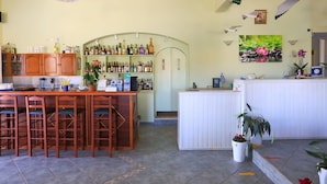 Een bar met houten krukken, een wit aanrecht en diverse flessen.