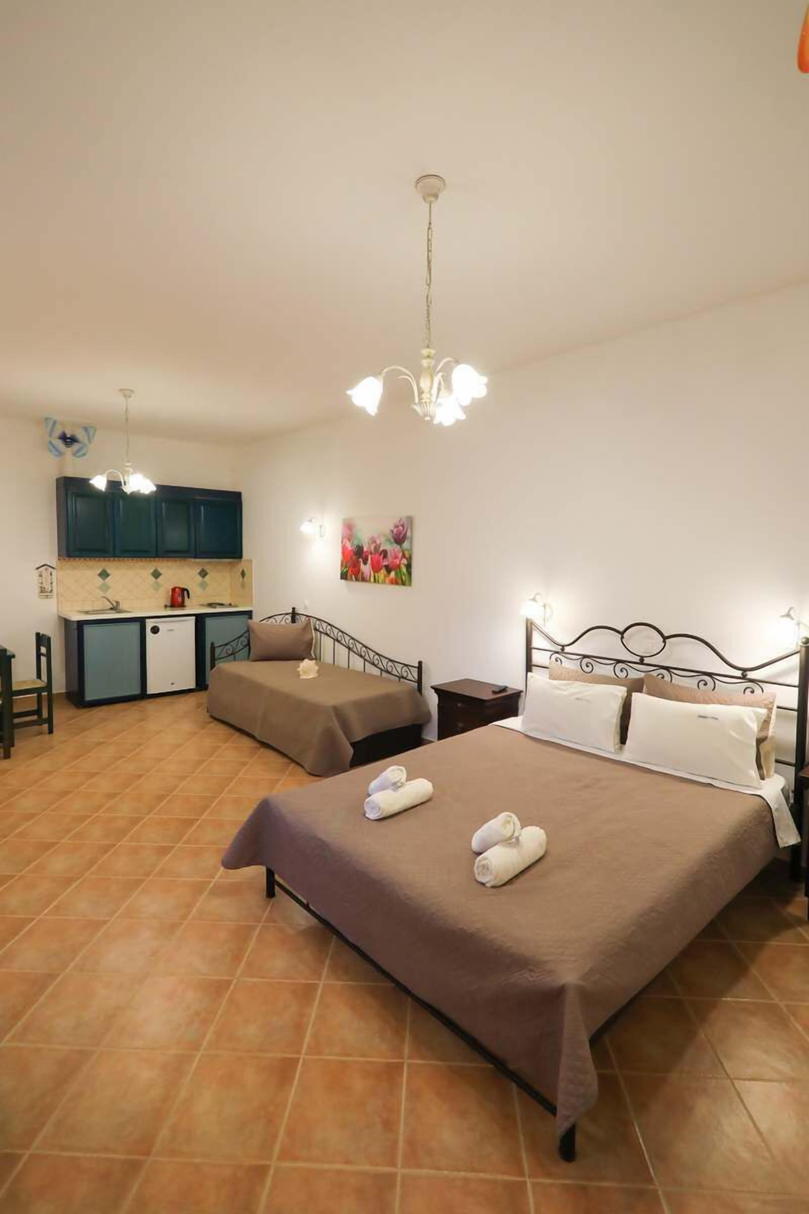 A bedroom with two beds, a kitchenette, and a dining area.