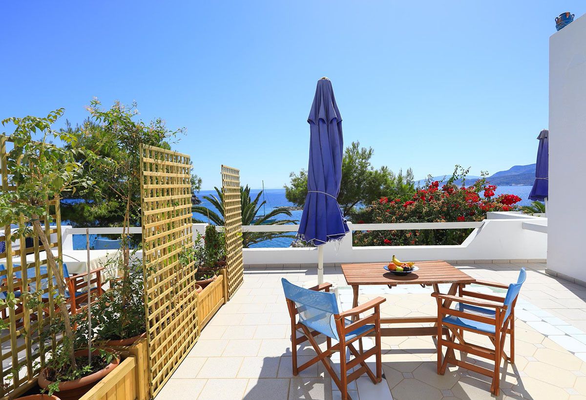 A terrace with a table and chairs, a wooden fence, and a view of the sea.