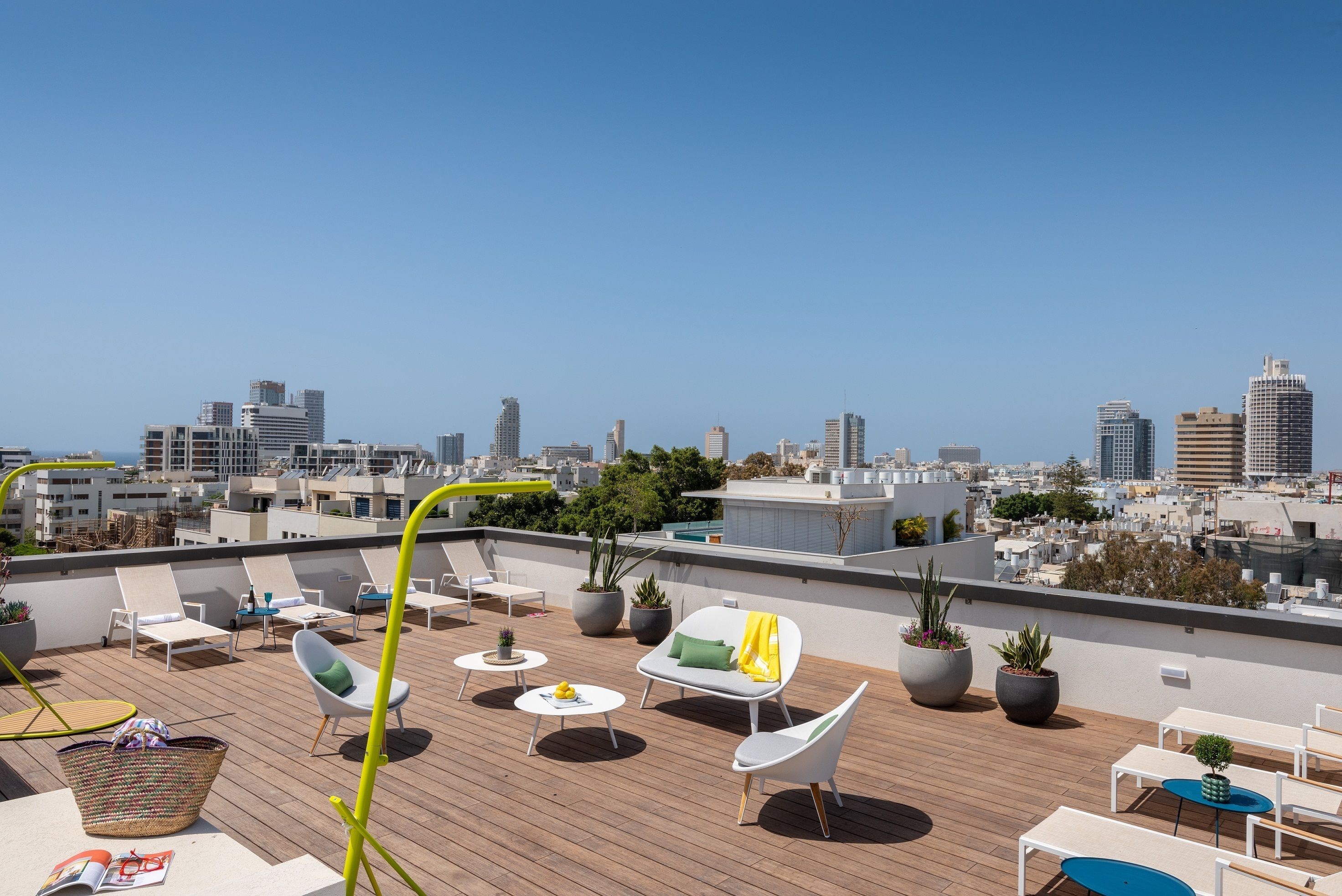 Una terraza en la azotea con sillones de descanso, mesas y plantas en macetas.