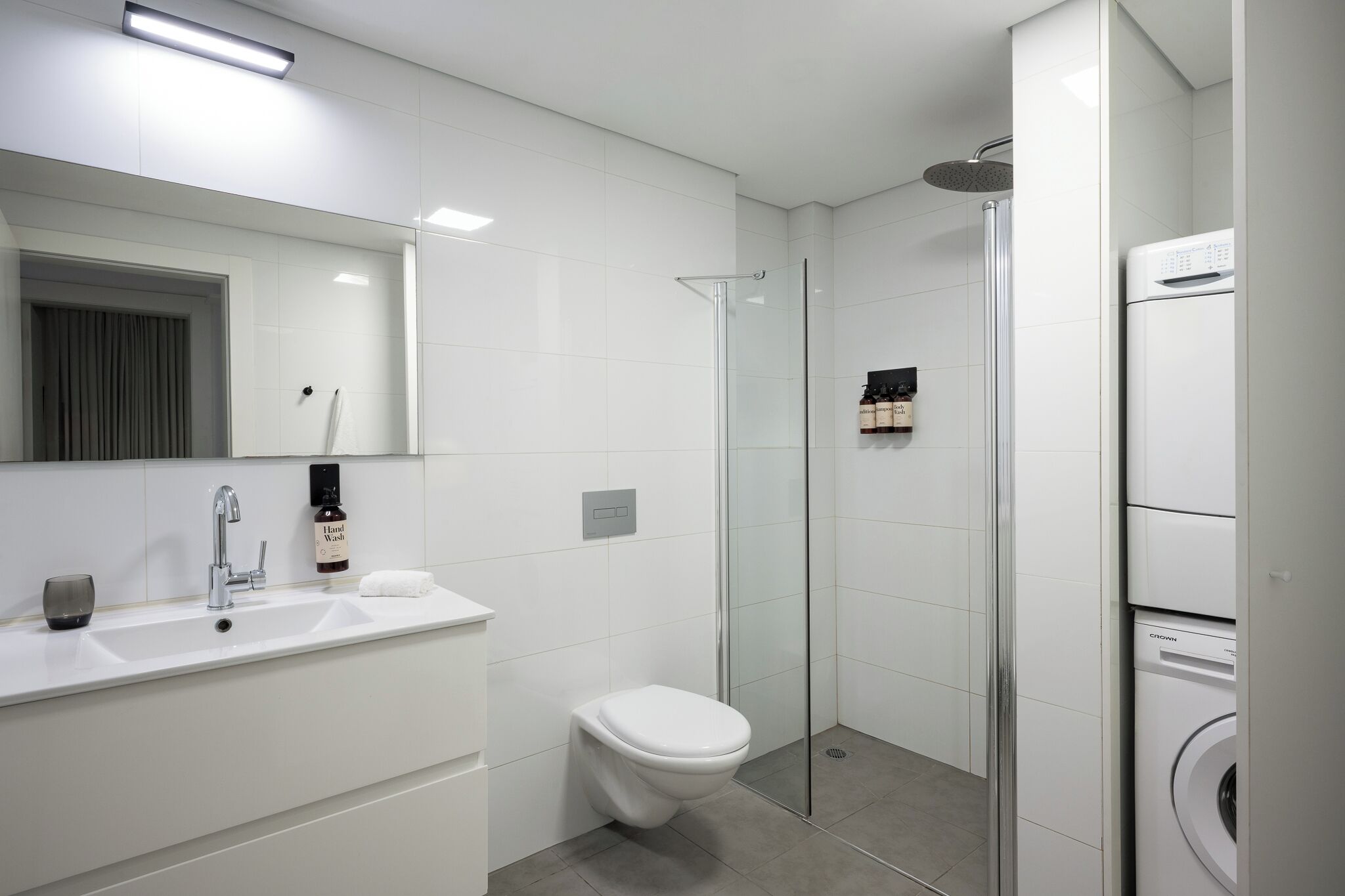 Une salle de bain moderne avec une douche à parois de verre, un lavabo blanc et des toilettes.