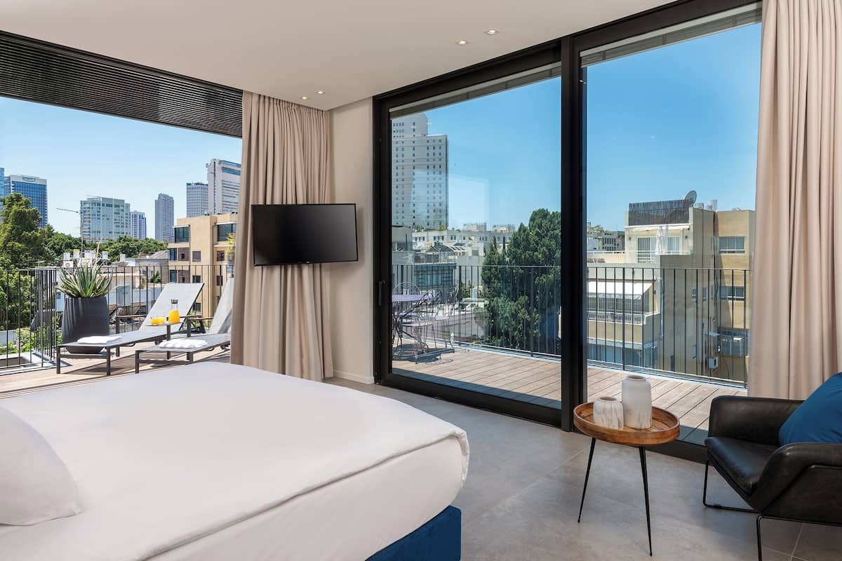 Ein Hotelzimmer mit Bett, Fernseher, Balkon mit Stadtblick und kleinem Tisch mit Tablett.