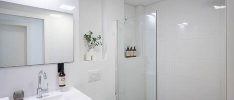 A modern bathroom with a white sink, a glass shower enclosure, and a mirror above the sink.