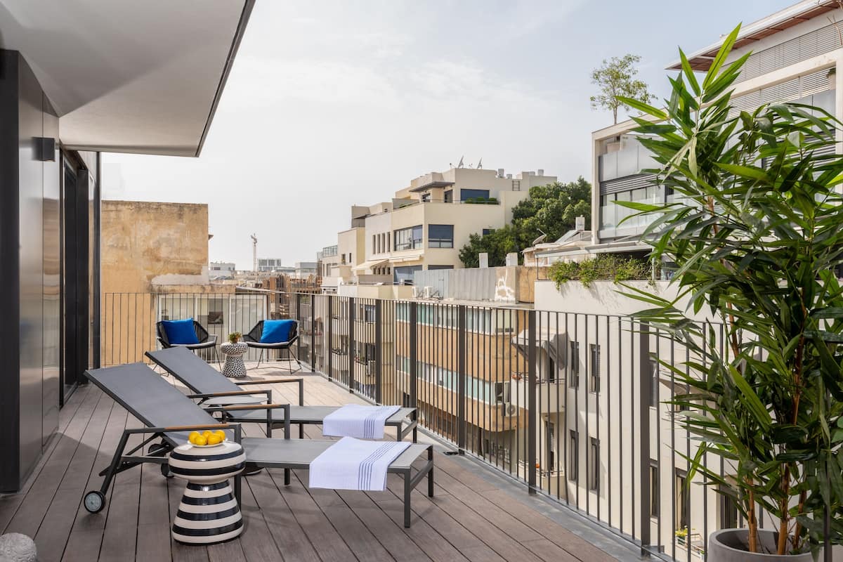 Eine Dachterrasse mit Liegestühlen, einem kleinen Tisch mit Zitronen und einem Blumentopf.