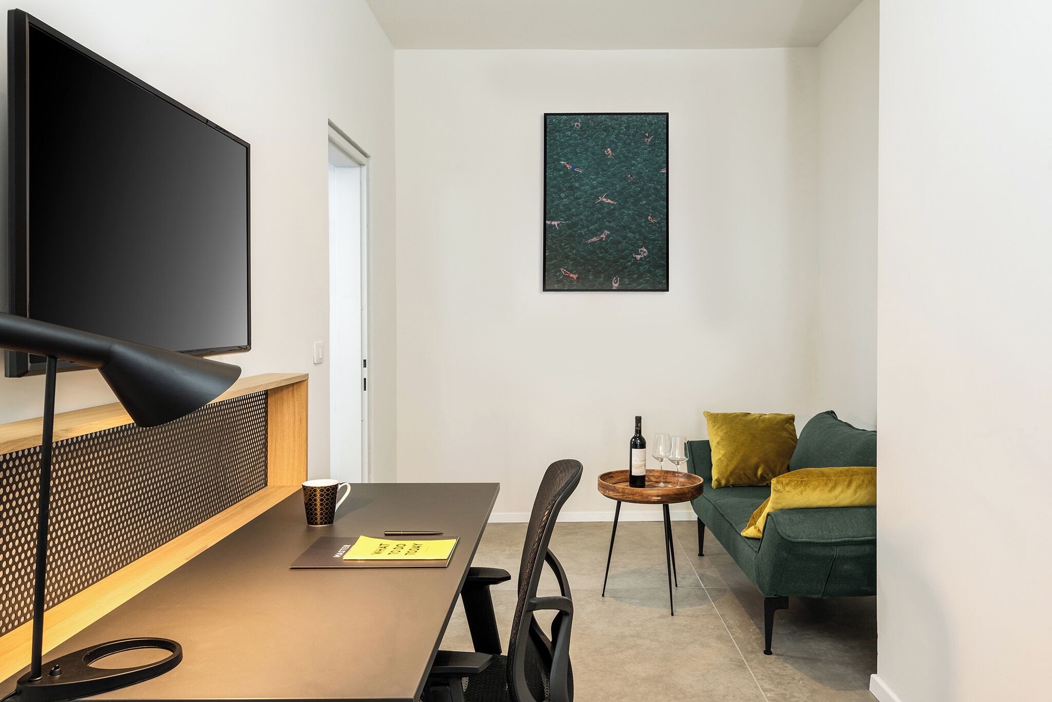 Una sala de estar moderna con un televisor de pantalla plana, una mesa de madera, un sofá y una obra de arte colgada en la pared.