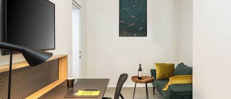 Una sala de estar moderna con un televisor de pantalla plana, una mesa de madera, un sofá y una obra de arte colgada en la pared.