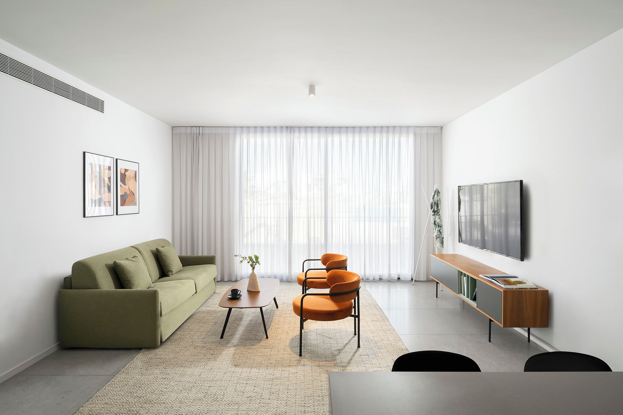 A modern living room with a sofa, a coffee table, a chair, a TV, and a bookshelf.