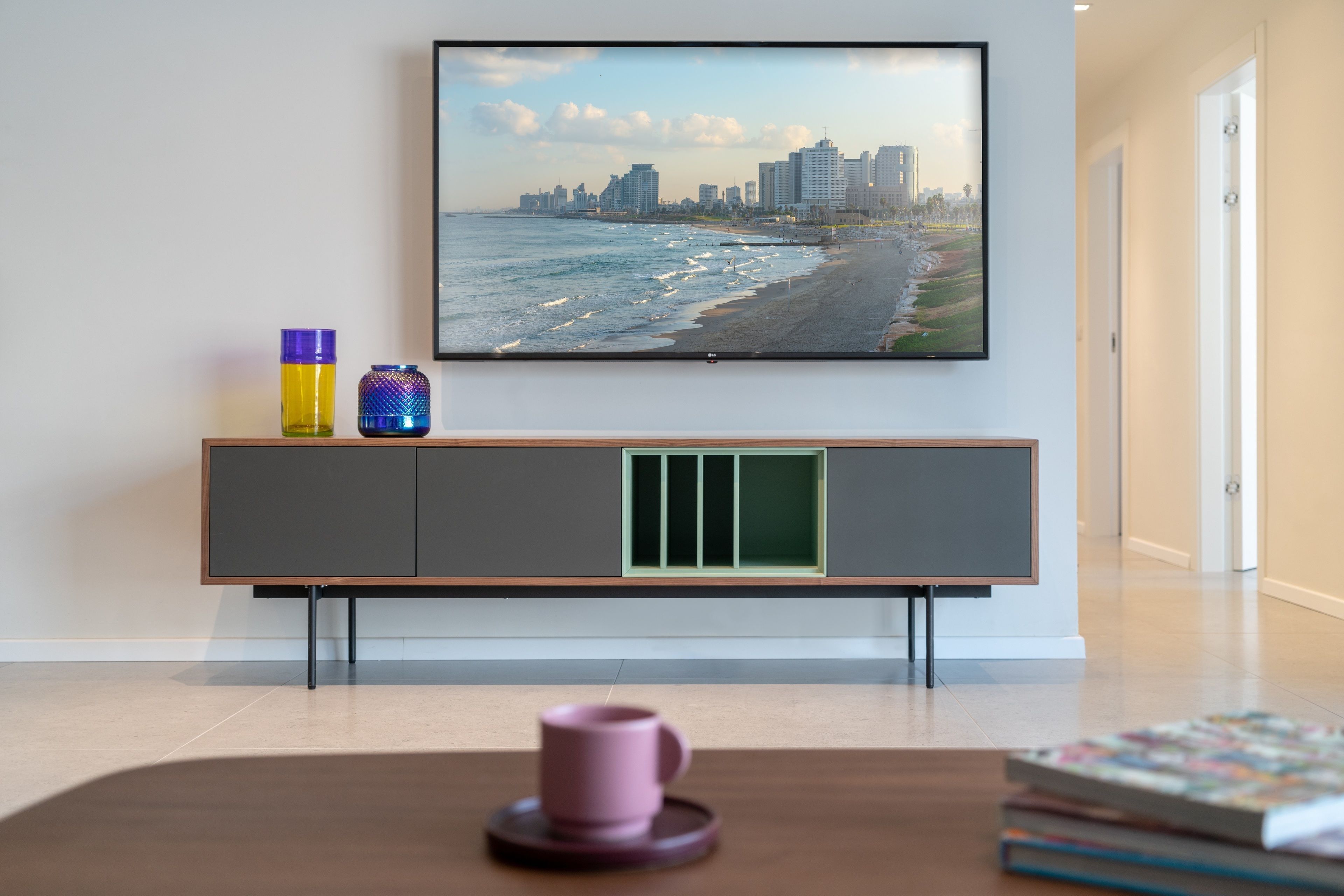 A modern living room with a flat-screen TV mounted on the wall displaying a cityscape.