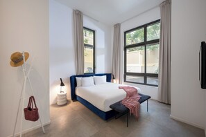 A bedroom with a bed, a bench, a lamp, and a hat on a stand. - master Shenkin (Tel Aviv)