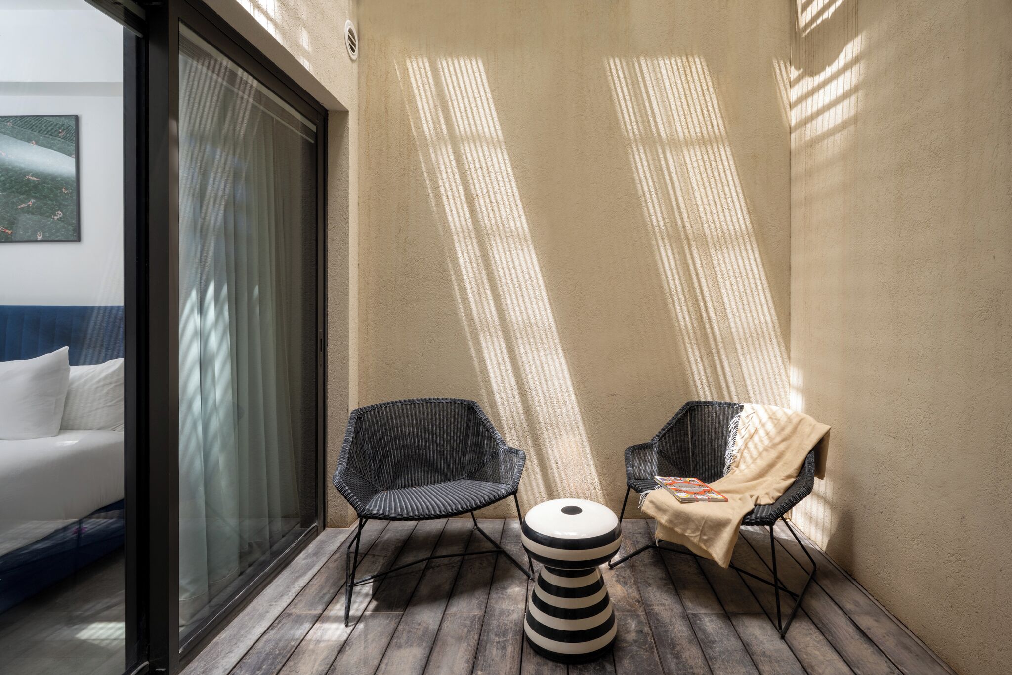 A balcony with two wicker chairs, a small round table, and a white sofa.