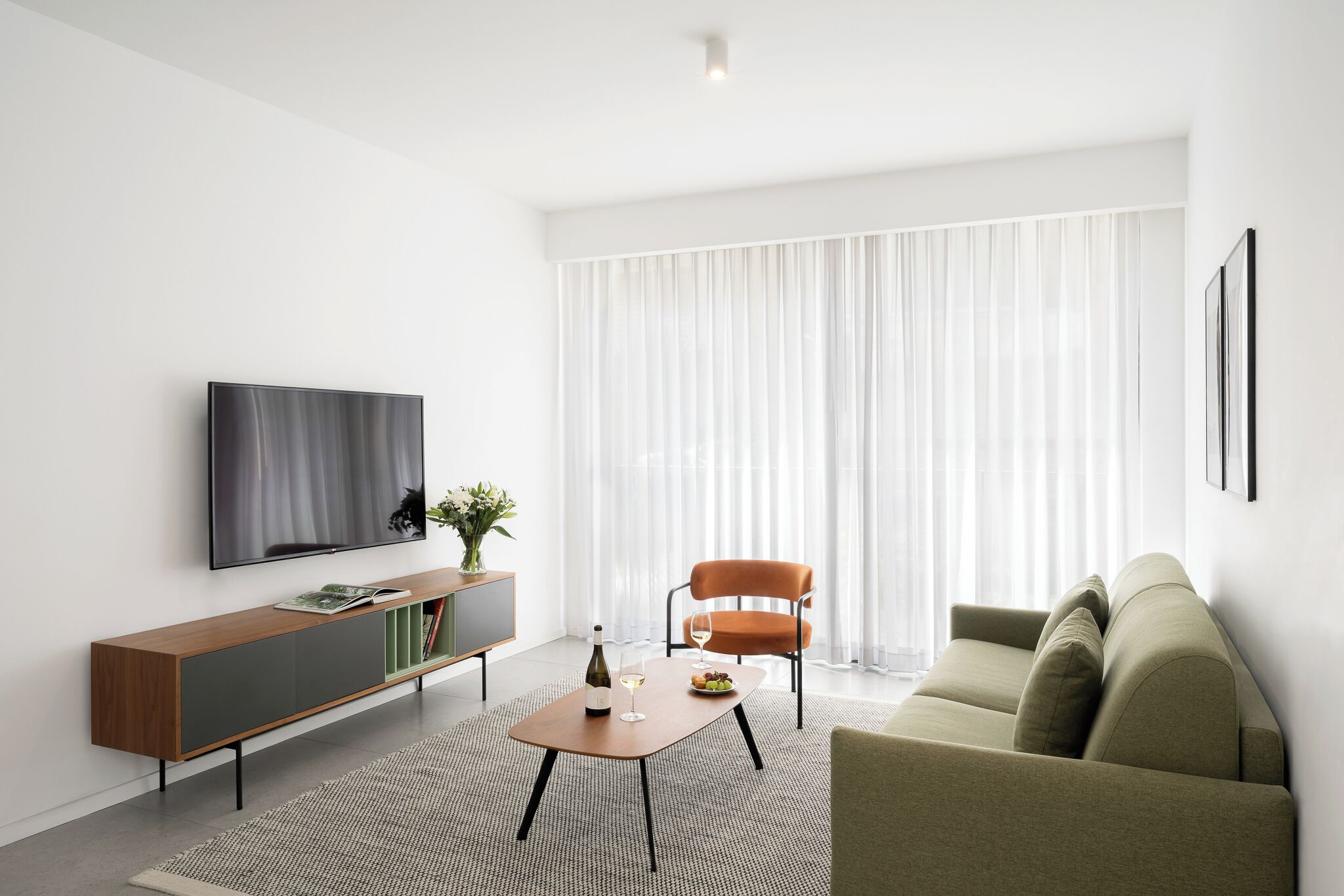 A modern living room with a flat-screen TV, a wooden console table, a sofa, and a chair.