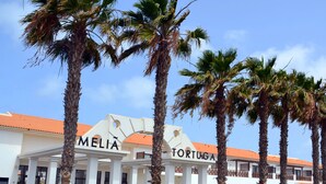 A hotel with a white facade, palm trees, and a sign reading "MELIA TORTUGA". - Private Self-Catering Apartments (Sal)