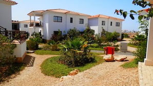 A residential area with white buildings, a gravel pathway, and greenery. - Private Self-Catering Apartments (Sal)