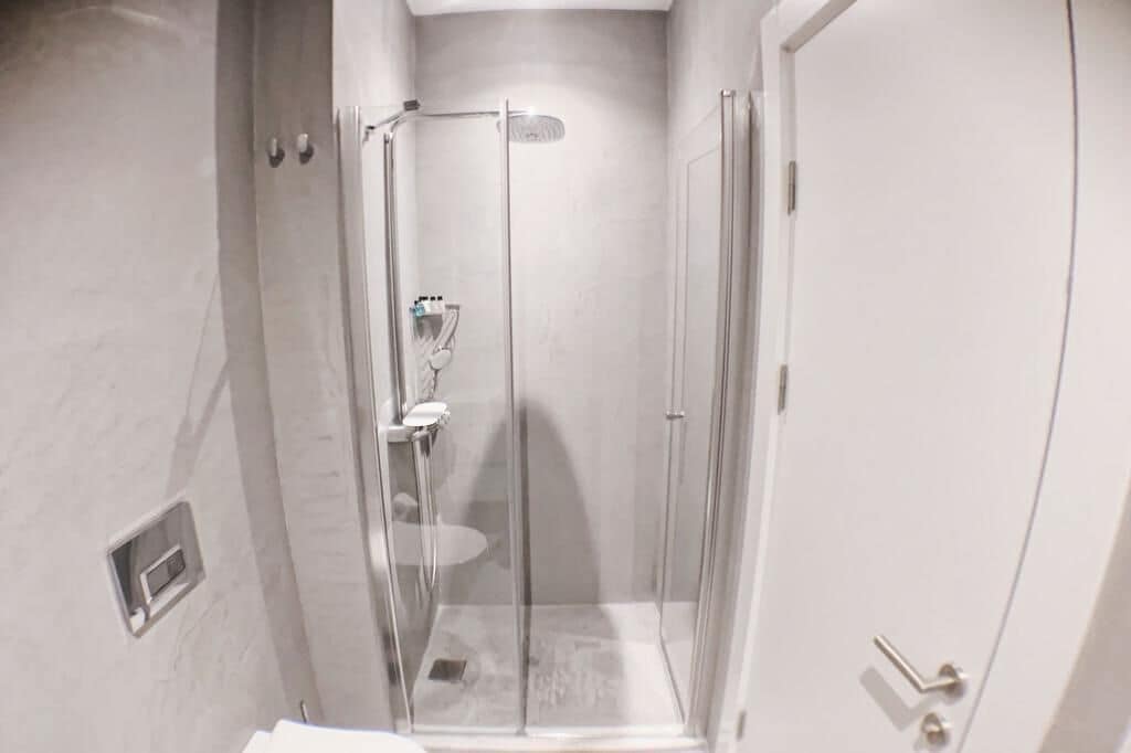 A glass-enclosed shower area with a white door and a small window on the wall.