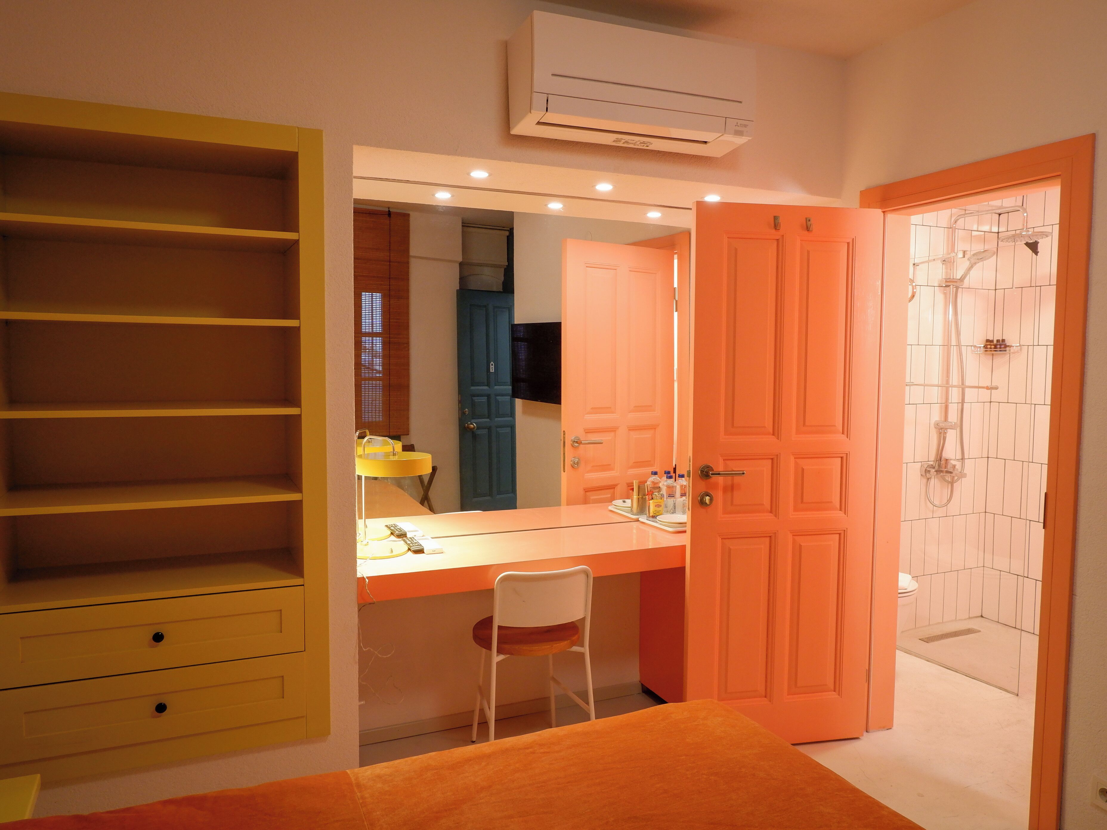 A bathroom with a shower, a sink with a mirror, and a yellow vanity.