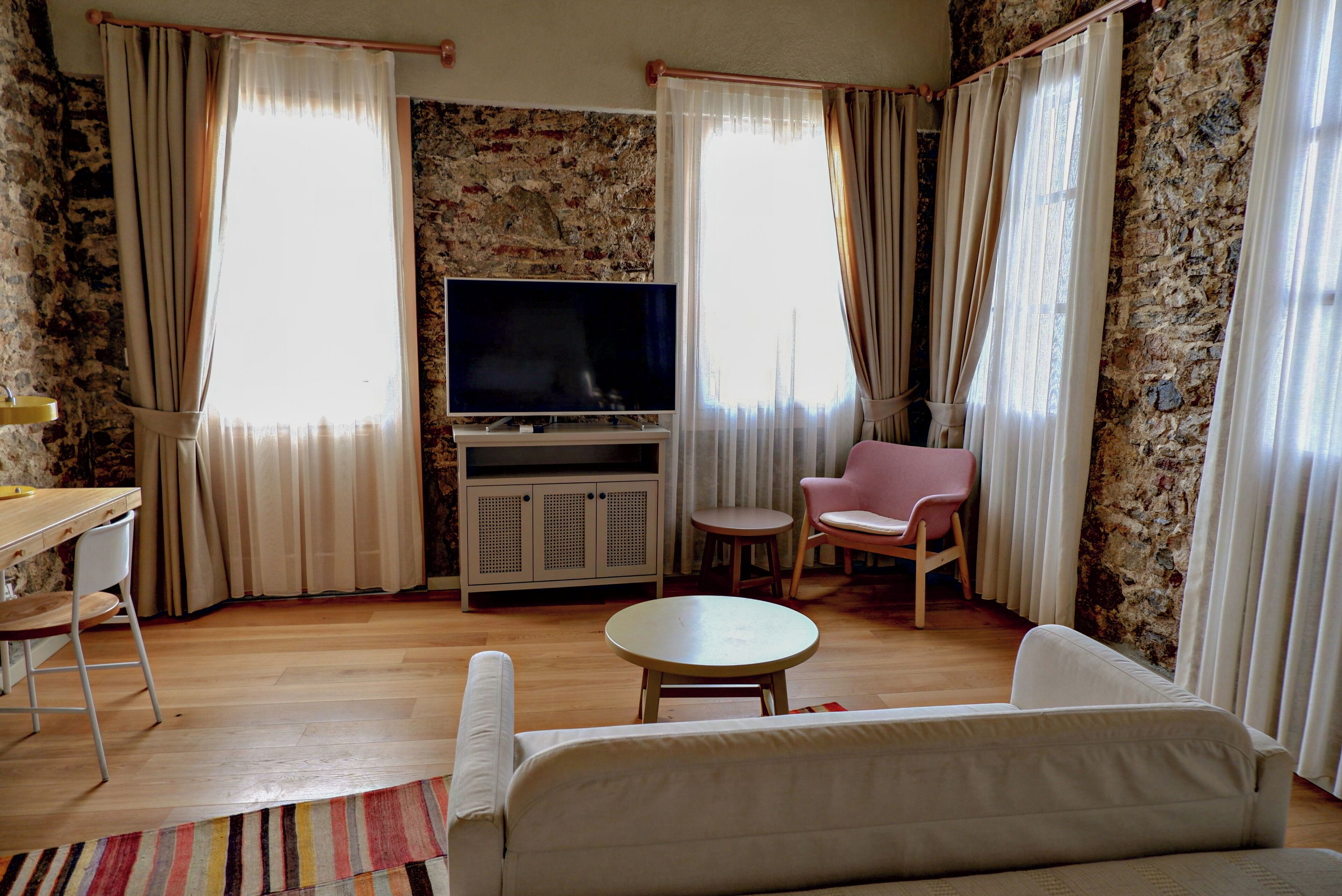 A living room with a sofa, a TV, a pink chair, and a small table.