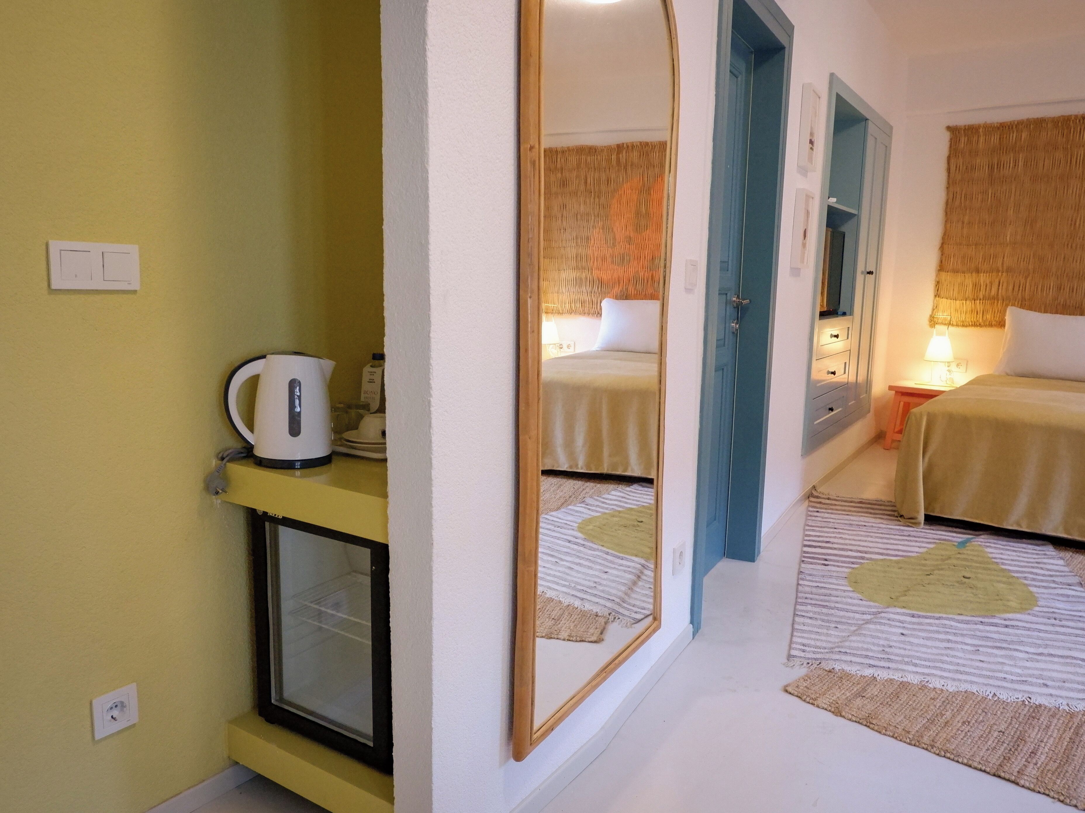 A hotel room with a bed, bedside table, lamp, and a mirror reflecting the room.