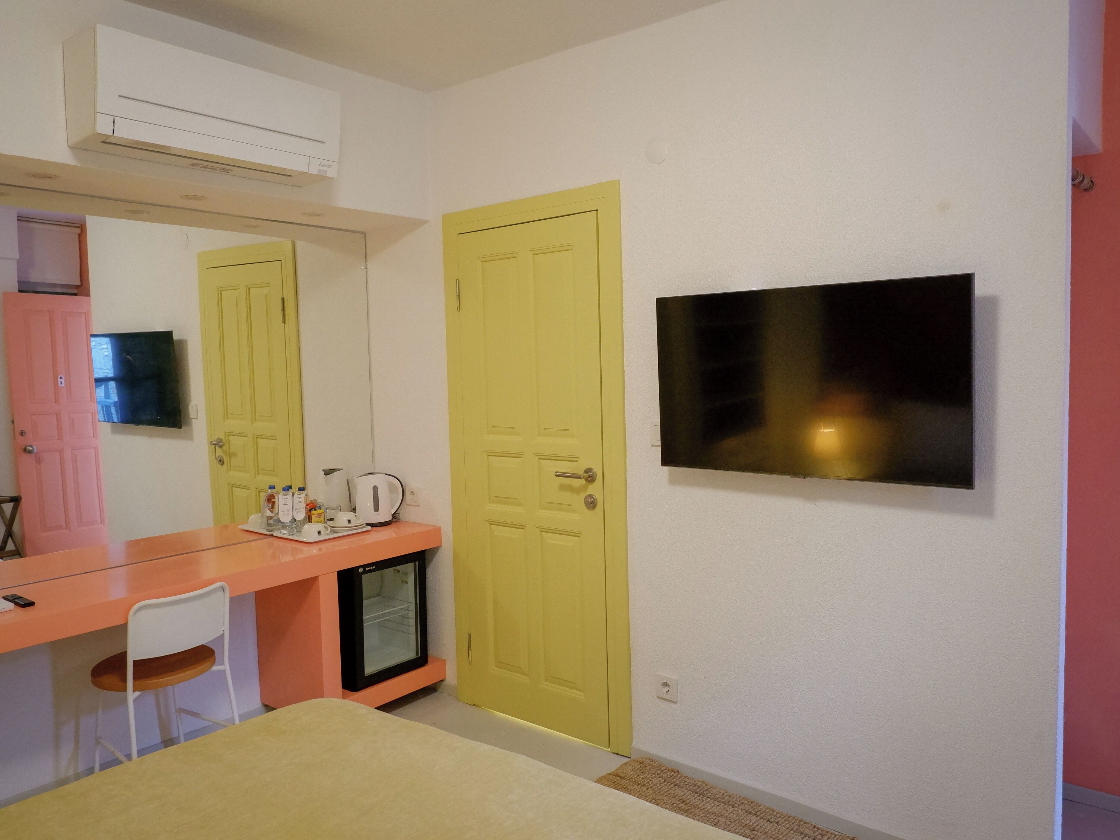 Una habitación con escritorio, silla y televisor montado en la pared.
