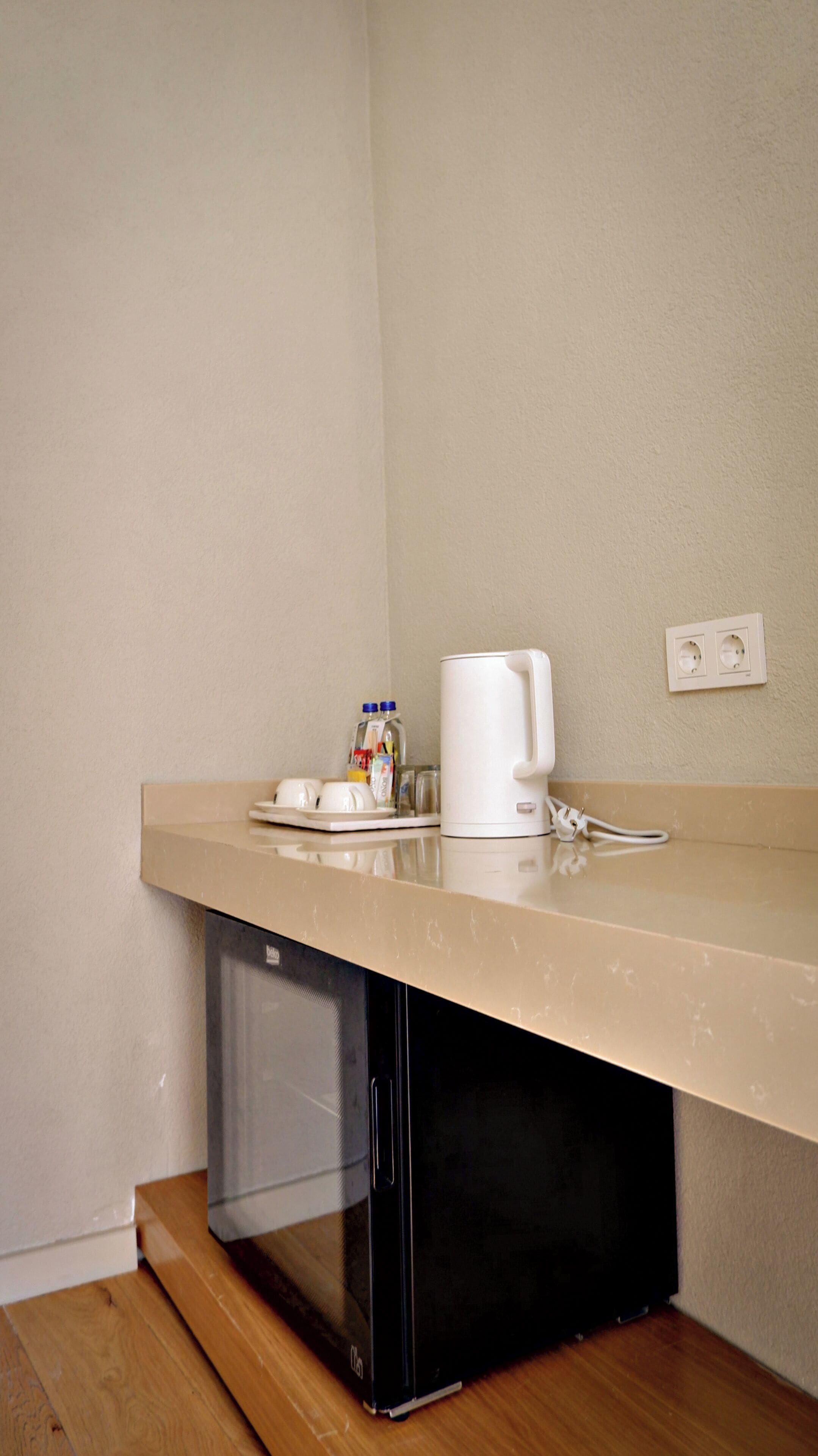 A kitchenette with a microwave, coffee maker, and a small countertop with a plate, cups, and condiments.