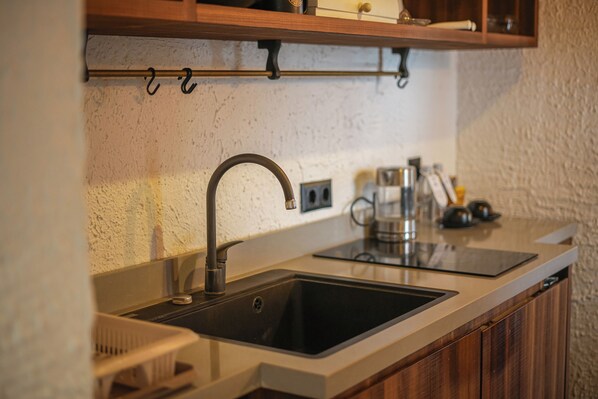 A kitchen with a stainless steel sink, wooden cabinets, and a countertop.