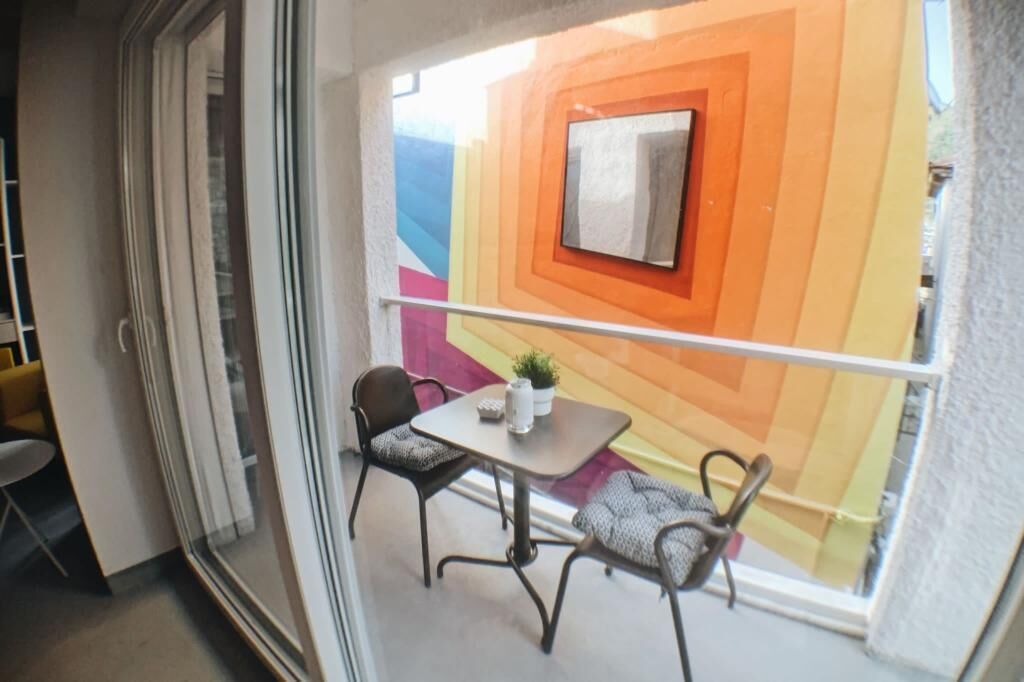 A balcony with a modern design, featuring a geometric wall pattern and a small table with two chairs.