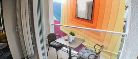 A balcony with a modern design, featuring a geometric wall pattern and a small table with two chairs.