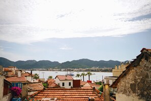 A coastal town with terracotta-roofed buildings, a marina with boats, and mountains in the background. - Bono Hotel Old Town (Marmaris)