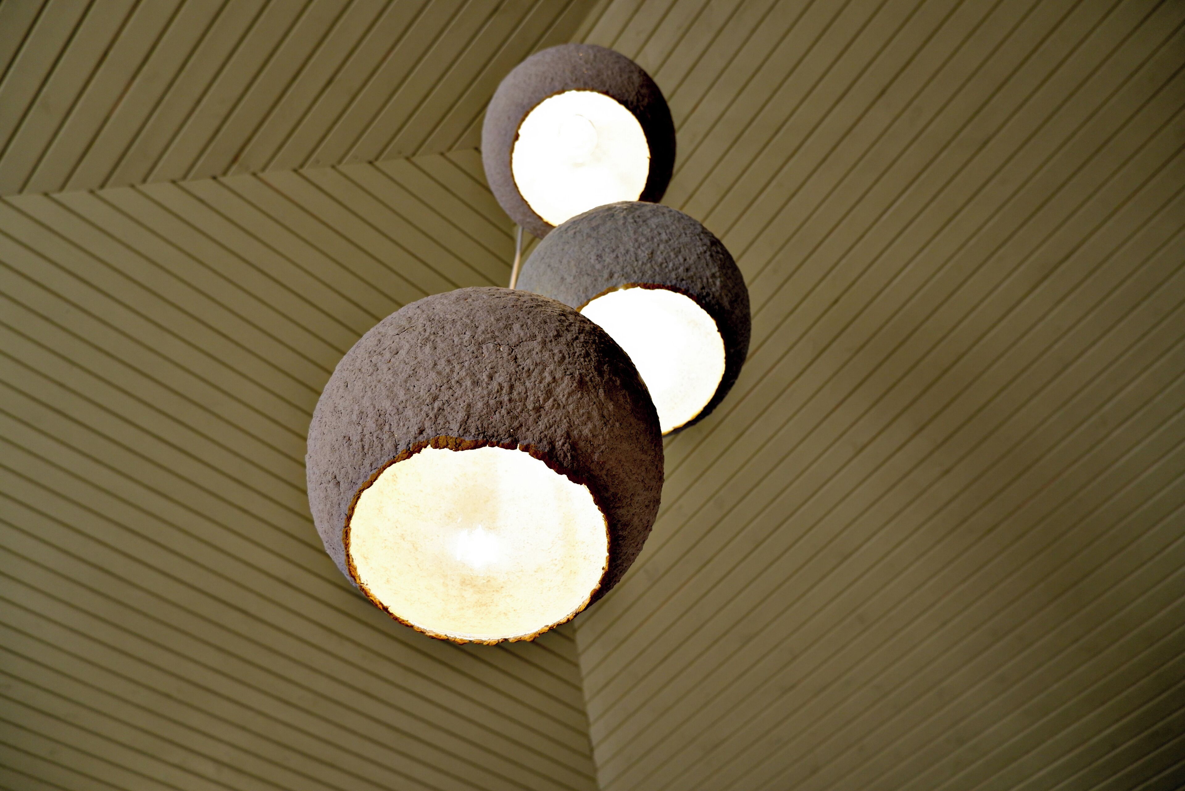 Un plafond orné d’un motif géométrique et trois luminaires sphériques.