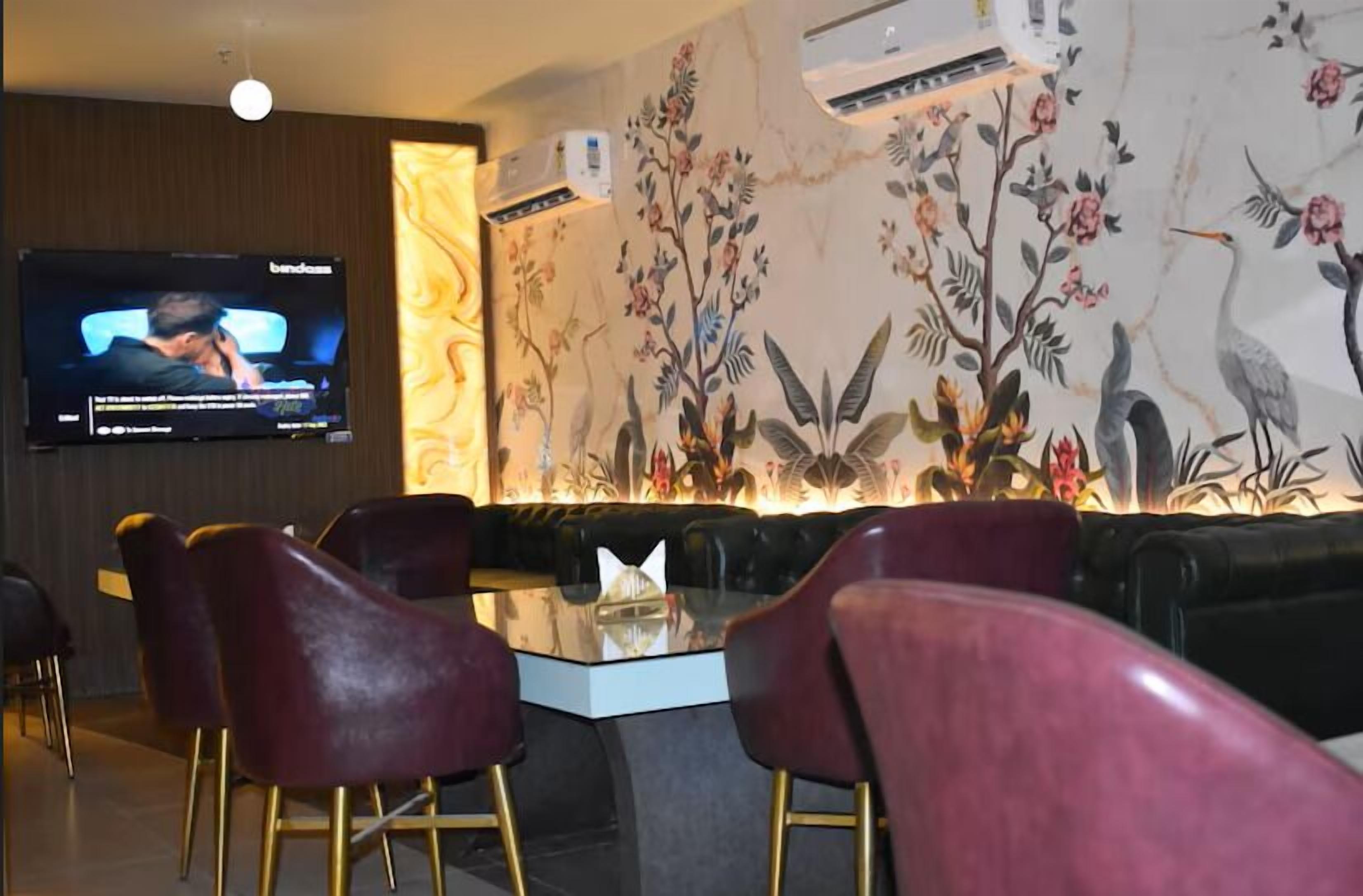 Un área de descanso moderna con televisor de pantalla plana, asientos cómodos y un mural decorativo.