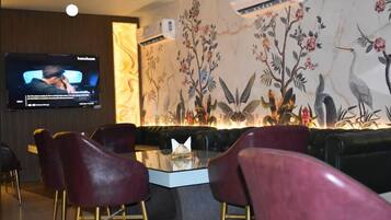Un área de descanso moderna con televisor de pantalla plana, asientos cómodos y un mural decorativo.