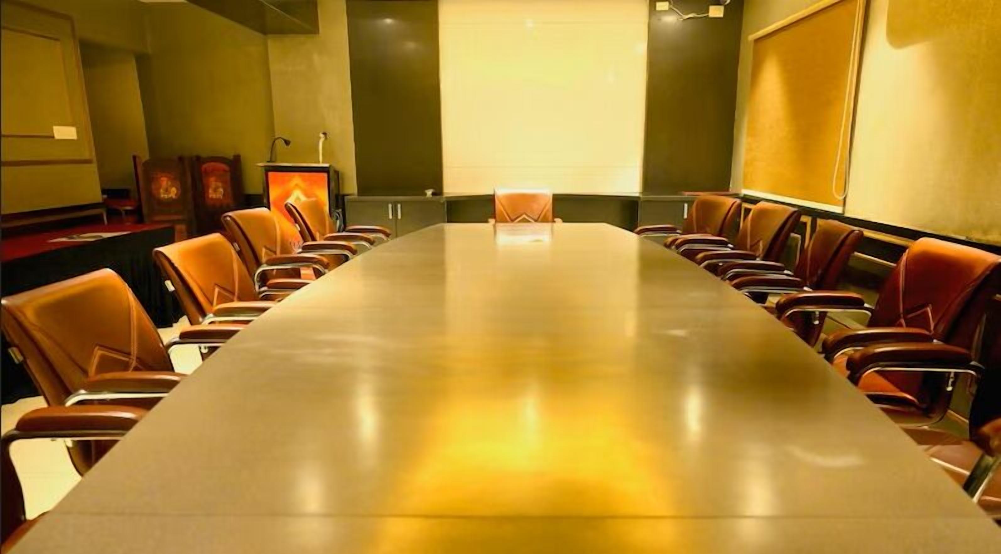 Una sala conferenze con un lungo tavolo e sedie, uno schermo per proiettore e uno schermo per presentazioni.