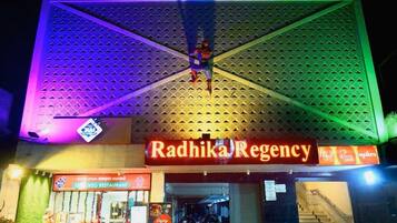 A building with a sign reading "Radhika Regency" and a vegetarian restaurant sign below it.