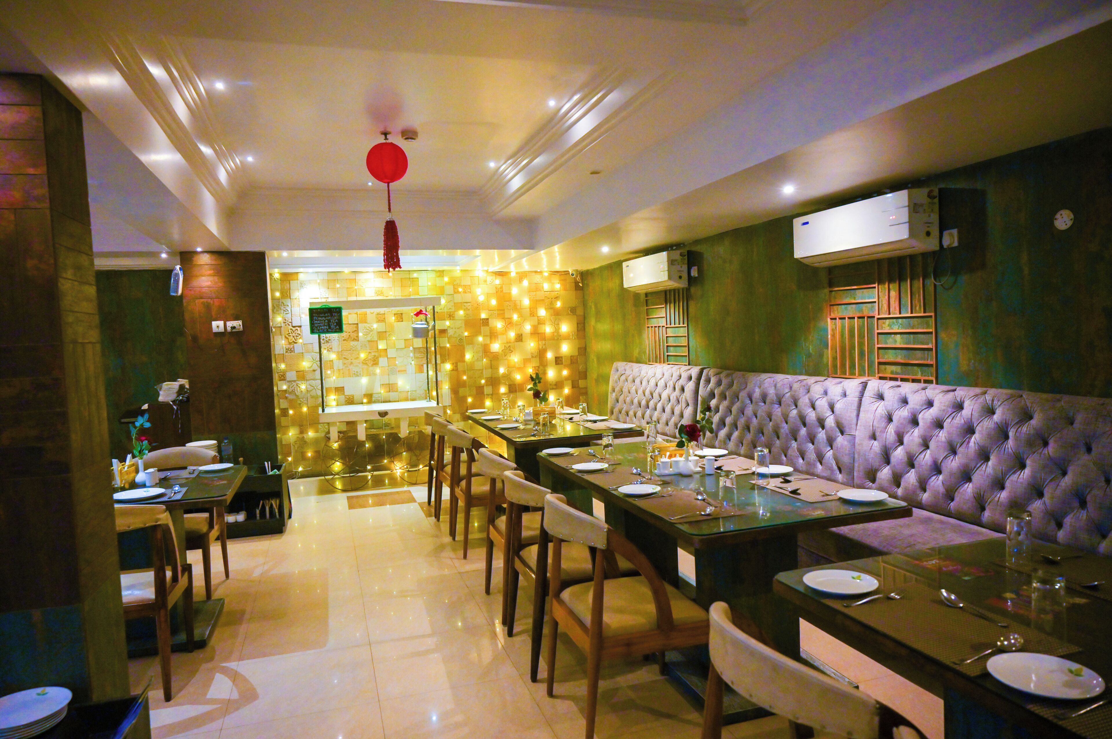 A dining area with a long table set for a meal, a cushioned bench, and a wall with a patterned design.