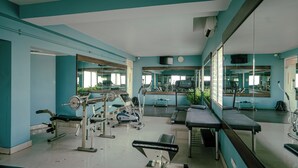 Et fitnesscenter med træningsudstyr, spejle og et turkis farvetema.