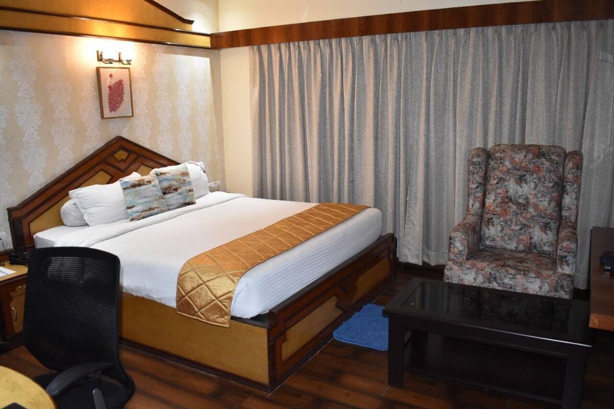 Una habitación de hotel con una cama, una silla, un escritorio y una mesita de centro.