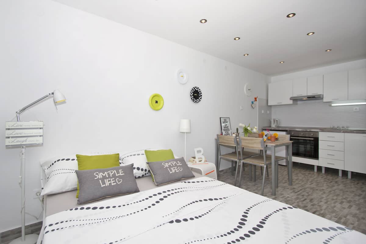 A modern bedroom with a bed, bedside table, and a small kitchenette.