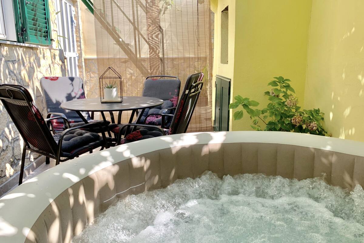 A hot tub with water, surrounded by outdoor furniture and plants.