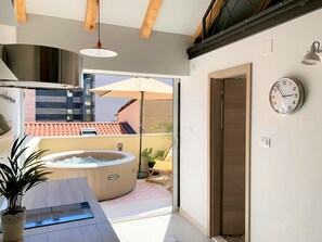 A modern bathroom with a bathtub, a sink, and a shower area. There is a clock on the wall and a view of the outside balcony. - Apartment Shiny Love (Split)