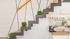 A modern kitchen with a wooden staircase, black metal railings, and green plants. - Apartment Shiny Love (Split)