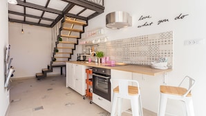 A modern kitchen with a wooden staircase, white bar stools, and a backsplash with geometric patterns. - Apartment Shiny Love (Split)