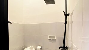 A small bathroom with a toilet, a shower, and a tiled floor.