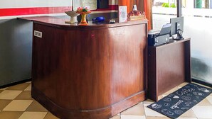 A reception desk with a "STAFF ONLY" sign, a decorative vase, a menu board, and a computer monitor.