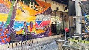 A hostel with a colorful mural, outdoor seating, and a small garden area.