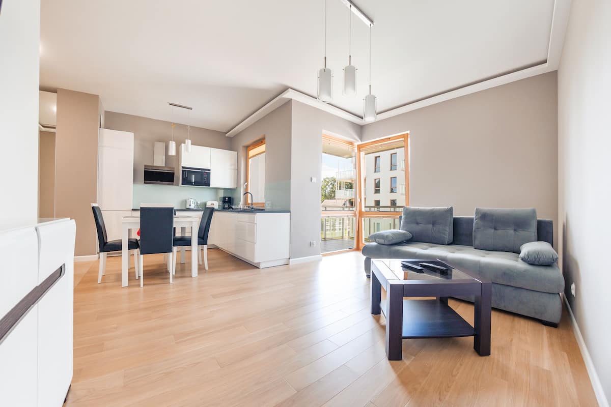 Una sala moderna con un sofá gris, una mesa de centro y un comedor con sillas y una mesa.
