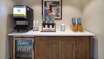 A kitchenette with a coffee machine, beverage dispensers, and a mini-fridge.