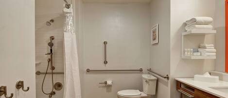 A bathroom with a shower, toilet, and sink, featuring a grab bar and a towel rack.
