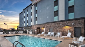 A hotel with a swimming pool, lounge chairs, and a stone facade. - Hampton Inn & Suites Tucson Tech Park (Tucson)