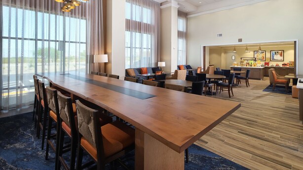 A spacious hotel lobby with a long wooden reception desk, multiple seating areas, and large windows offering views of the outdoors. - Hampton Inn & Suites Tucson Tech Park (Tucson)